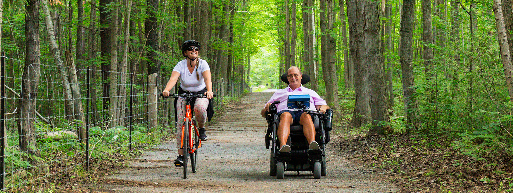 A cyclist and a person in a wheelchair enjoying an accessible trail in the York Regional Forest A cyclist and a person in a wheelchair enjoying an accessible trail in the York Regional Forest