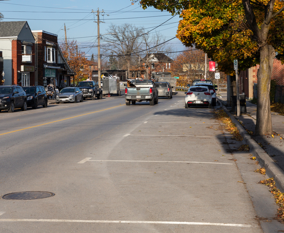 a road with lines painted beside a sidewalk indicating parking spots